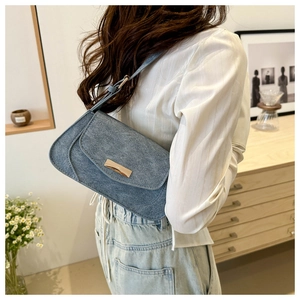 Detailed shot of retro blue denim baguette bag featuring a gold rectangular buckle
