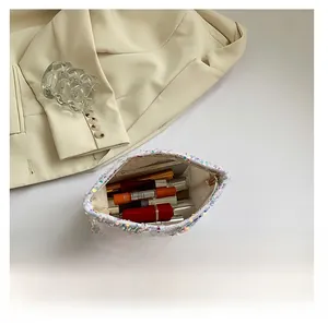 Detail view of the spacious inner compartment of the sequined makeup pouch with cosmetics