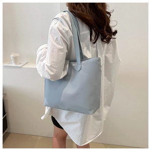 Side view of model wearing a light blue large nylon tote bag with long handles