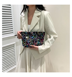 Close-up of a colorful sequined handbag held by a model in a minimal setting