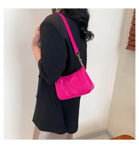 Détail du sac laqué rose vif avec papillon embossé et maillons de chaîne métalliques
