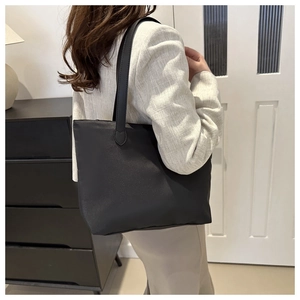 Detail of a large black nylon tote bag with matte texture on a casual outfit