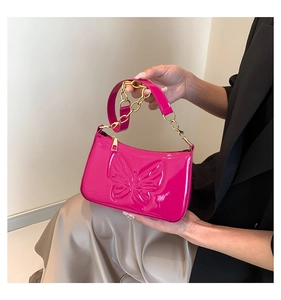 Détail du sac baguette en cuir verni rose vif avec des motifs papillons en relief