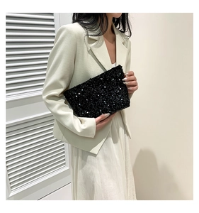 Detail of elegant black sequin evening handbag styled with a minimalist white suit