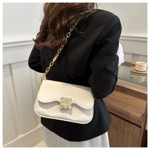 Detailed view of the wavy flap and golden bear buckle on a cream saddle bag