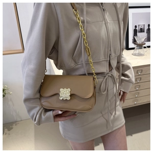 Detailed close-up of light brown crossbody saddle bag featuring a golden bear-shaped lock