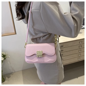 Close-up of pink PU leather saddle bag with golden bear metal clasp and chain detail