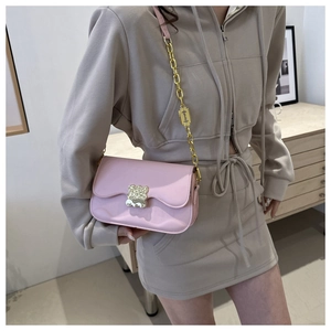 Pink saddle bag featuring a bear turn-lock and razor-shaped metal chain detail