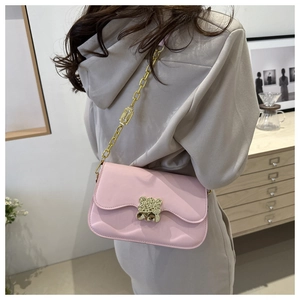 Detail of pink saddle bag with golden bear buckle and metal chain strap shown on model