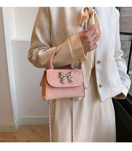 Détail d'un mini sac à main rose avec nœud métallique argenté et bandoulière chaîne