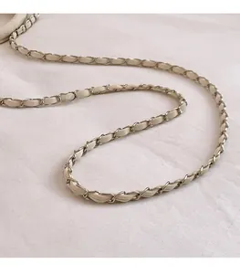 Détail d'une bandoulière en chaîne dorée tressée de cuir beige pour sacs à bandoulière