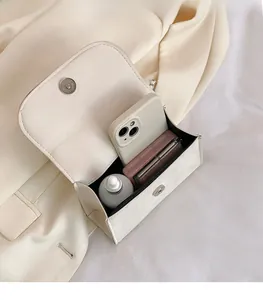 Vue détaillée de l'intérieur du petit sac crème montrant l'espace pour téléphone et maquillage