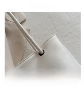 Close-up of cream white leather tote bag showing metal eyelets and pebble texture detail