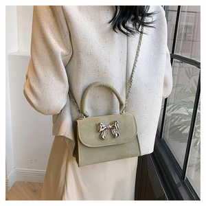 Détail du sac bandoulière vert haricot avec boucle nœud argenté sur veste beige