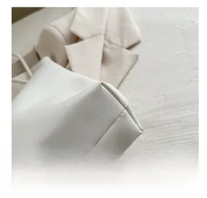 Detailed close-up of premium lychee grain texture and stitching on off-white tote bag
