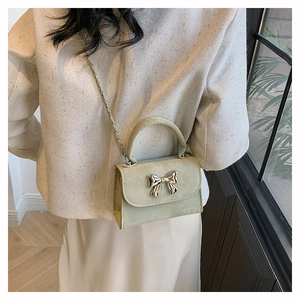 Détail du mini sac à main vert menthe avec boucle nœud dorée et bandoulière chaîne