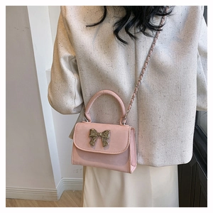 Vue détaillée du sac à bandoulière rose avec fermoir nœud doré sur veste en tweed
