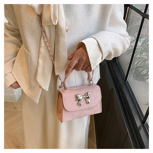 Détail du mini sac à main rose avec nœud argenté et bandoulière chaîne sur modèle