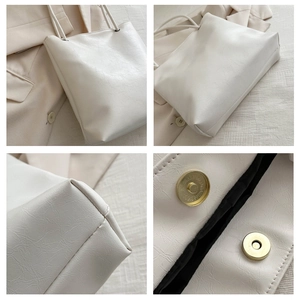 Detail view of large white tote bag showing magnetic buckle and crackle texture leather