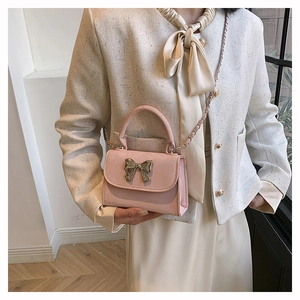 Détail d'un sac à main rose avec fermoir noeud en métal doré et bandoulière chaîne