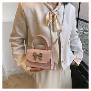 Vue détaillée d'un mini sac rose avec nœud métallique et fine bandoulière chaîne