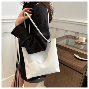 Detail shot of the reinforced eyelets and soft white PU leather texture on the tote bag
