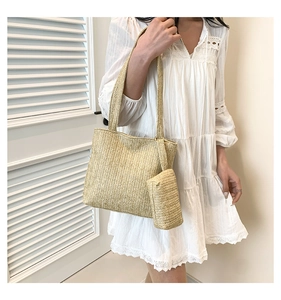 Detail of straw woven tote bag set with matching pouch on model for a summer beach look
