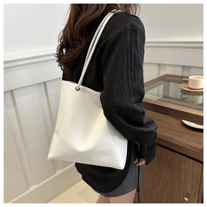 Minimalist white tote bag showing soft synthetic leather texture and metallic ring detail
