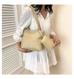 Close-up of woven straw tote bag with matching inner pouch on a white lace dress