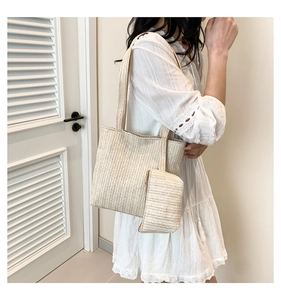 Detail view of woven straw tote bag and detachable pouch on model in white lace dress