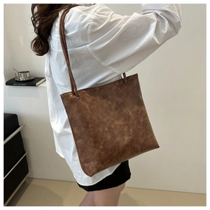 Brown large capacity tote bag with oil wax leather texture shown on model shoulder