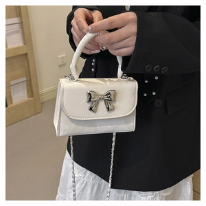 Détail du nœud métallique argenté et de la bandoulière sur un sac à main carré crème