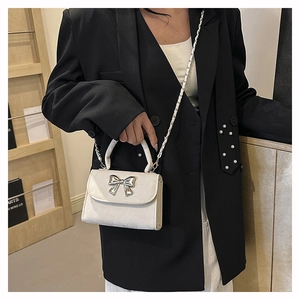 Détail du mini sac en velours blanc avec gros nœud argenté et bandoulière chaîne