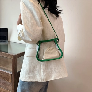 Minimalist transparent PVC tote bag with green leather trim and beige drawstring inner pouch