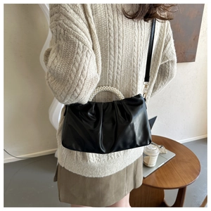 Detail of black pleated cloud bag with pearl handle and slim shoulder strap