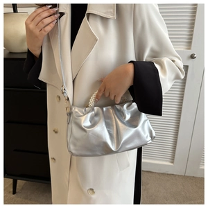 Detail of silver pleated cloud bag featuring a pearl bead handle and slim shoulder strap