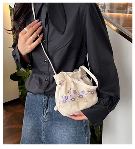 Détail du petit sac seau en toile beige avec broderie florale violette sur mannequin