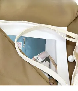 Détail du sac en toile kaki avec anse tressée blanche, perles larges et boutons rétro