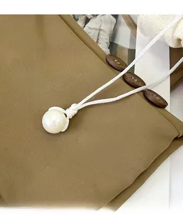 Détail du cordon tressé blanc avec perle sur un sac en tissu de couleur kaki