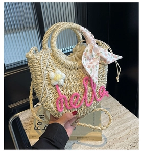Detail of hand-woven straw bag with pink hello text and floral scarf handle