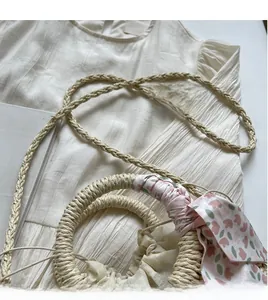 Detail of straw handbag with floral silk scarf handle and smooth long shoulder strap