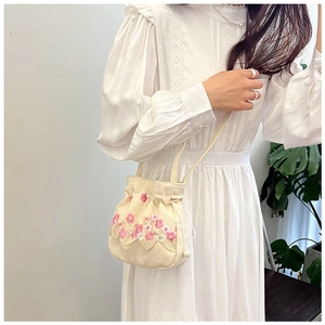 Détail du sac bandoulière brodé de fleurs avec dentelle et perle sur le cordon de serrage