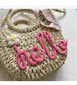 Detail of straw bag with hello embroidery, crochet flower and floral silk scarf handle