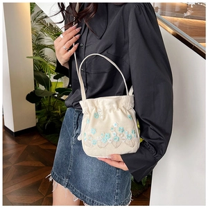 Détail de la broderie florale sur sac seau en toile crème avec poignée de transport