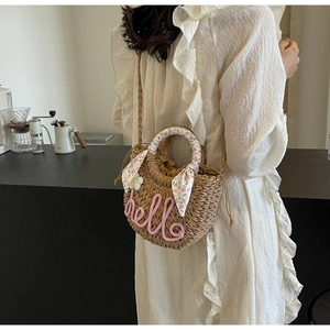 Detail of straw woven tote with pink hello embroidery and floral silk scarf accessory