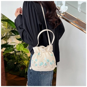 Détail d'un sac seau en toile avec broderie florale et cordon perlé élégant