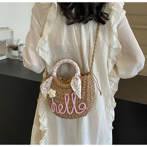 Detailed back view of a woven straw beach bag with pink hello embroidery and silk handle