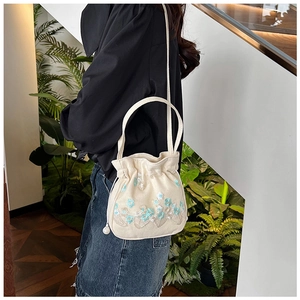 Détail d'un sac à cordon en toile blanc cassé avec une broderie florale délicate