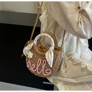 Detail of round straw beach bag with pink hello embroidery and floral scarf handle