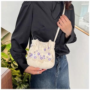 Gros plan détaillé d'une broderie florale sur un sac en toile blanc avec cordon de serrage